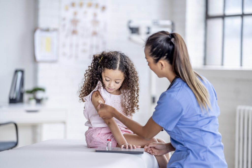 Operatore sanitario vaccina una bambina contro il virus influenzale.
